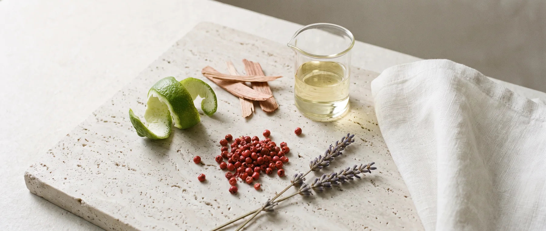 Bergamotteschale, Zedernholz, rosa Pfeffer, Lavendel und ein Glas Duftöl auf Travertin
